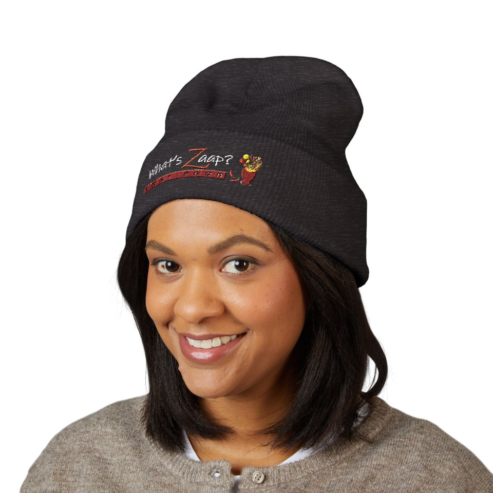 Smiling woman with shoulder-length dark hair wearing a black embroidered “What’s Zapp?” beanie and gray sweater.