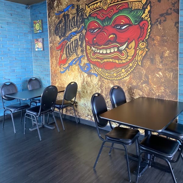 Interior of What's Zaap? Thai Food, with black tables and chairs, and a large Thai mural.