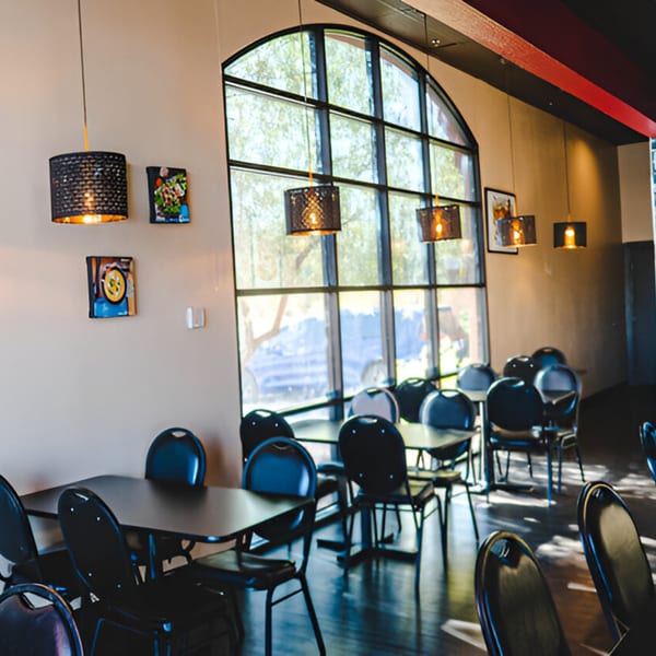 Interior of What's Zaap? Thai Food, featuring tables, chairs, and a large arched window.
