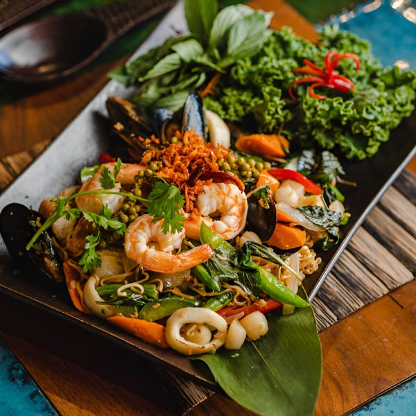 A vibrant Thai seafood stir-fry with shrimp, mussels, squid, noodles, and fresh herbs.