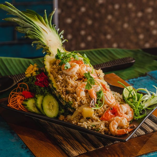 Thai pineapple fried rice with shrimp, vegetables, and lime, served in a pineapple half.
