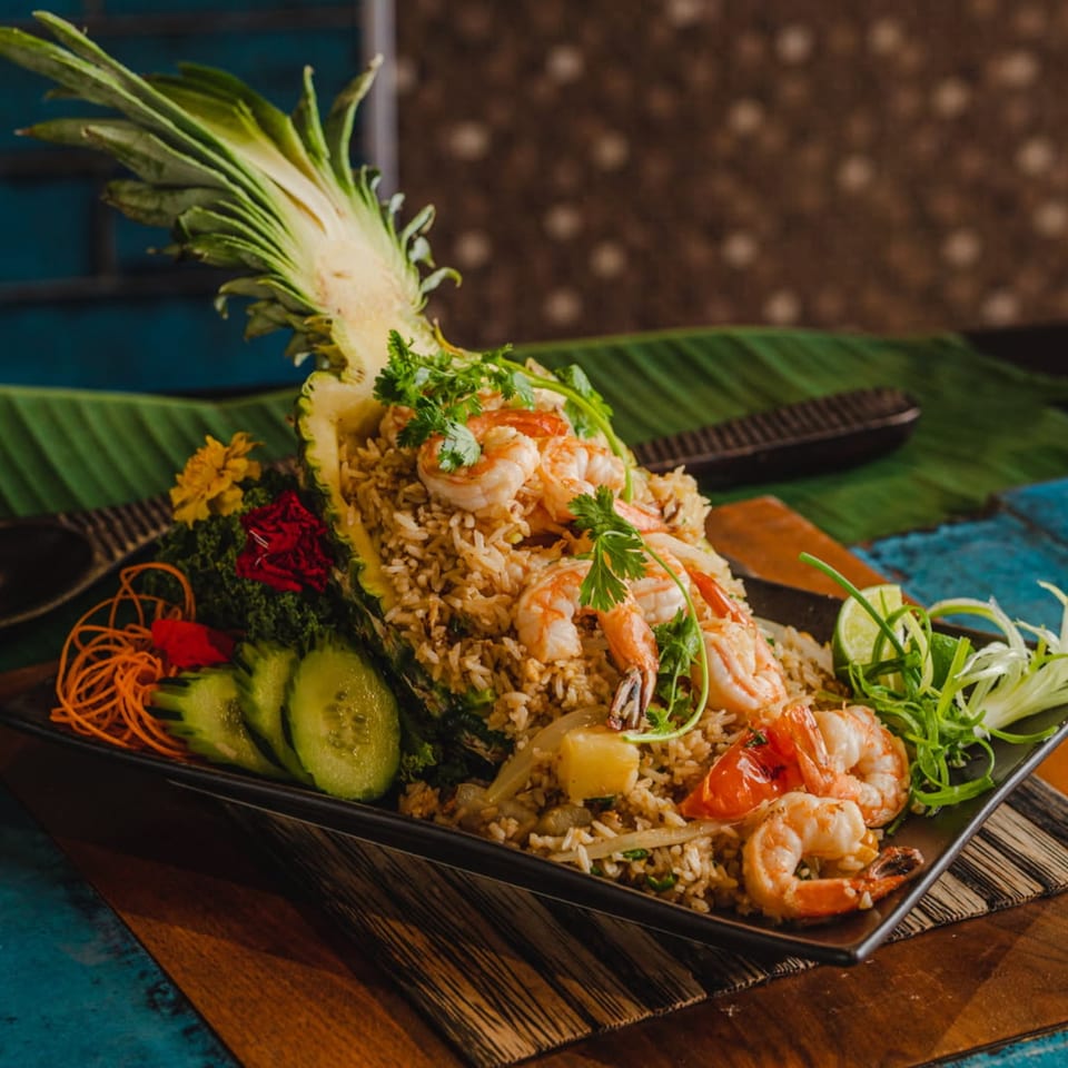 Thai pineapple fried rice with shrimp, vegetables, and lime, served in a pineapple half.